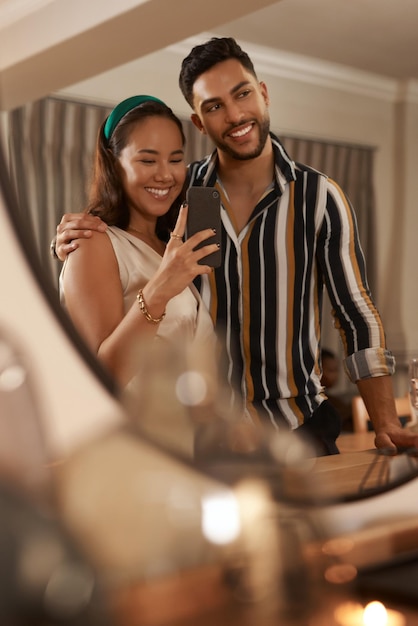 Celebración de la cena y pareja con selfie en un teléfono en el espejo disfrutan del festival navideño y la fiesta de Navidad Restaurante de eventos sociales y jóvenes hombres y mujeres felices toman fotos con un teléfono inteligente
