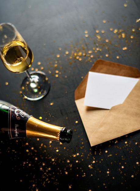 Celebración con champagne y tarjeta en mesa negro.