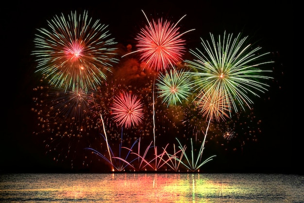 Celebración de coloridos fuegos artificiales desde el mar con el cielo de medianoche