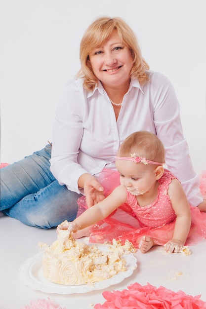 Celebración de cumpleaños: niña comiendo pastel con las manos en blanco. el niño está cubierto de comida. arruinada dulzura.