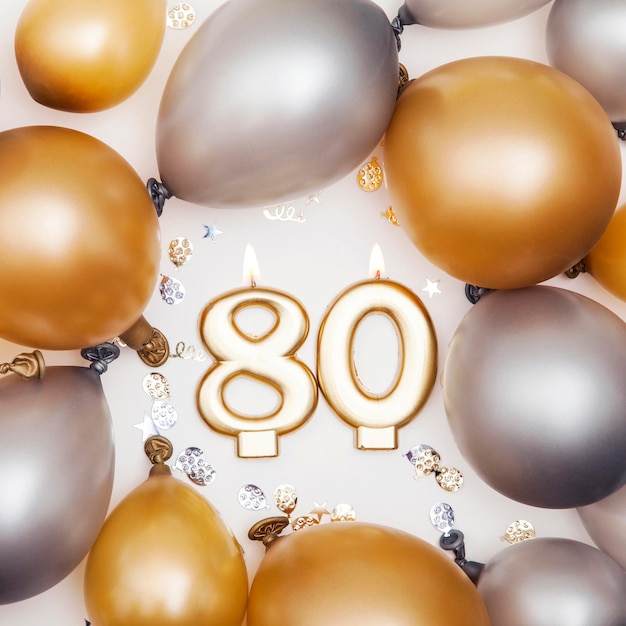 Celebración de cumpleaños vela número 80 con globos dorados y plateados