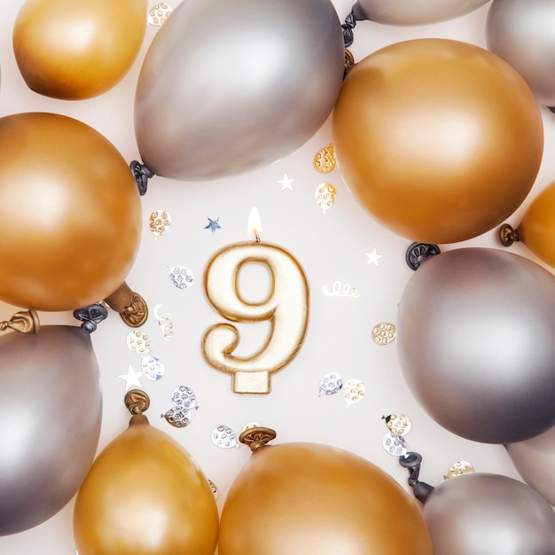 Celebración de cumpleaños vela número 9 con globos dorados y plateados