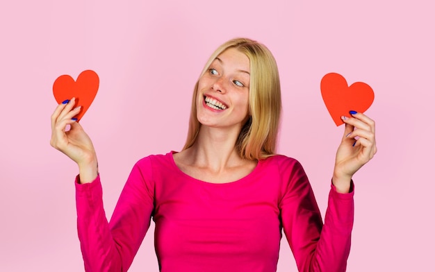 Celebración del día de san valentín chica rubia con dos corazones de papel rojo en relaciones de manos