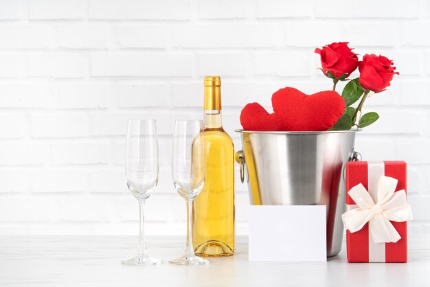 Celebración del día de San Valentín con vino, regalo y ramo de rosas para saludo navideño.