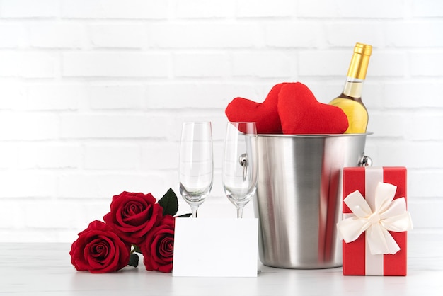 Celebración del día de San Valentín con vino, regalo y ramo de rosas para saludo navideño.