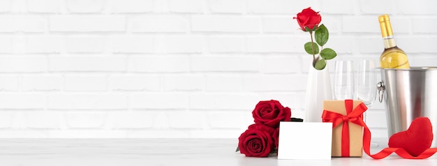 Celebración del día de San Valentín con vino, regalo y ramo de rosas para saludo navideño.