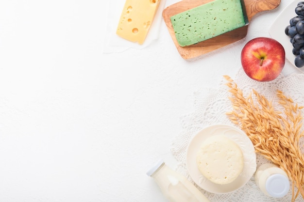 Celebración festiva judía de Shavuot Leche y queso trigo maduro y frutas fondo de madera azul Productos lácteos sobre fondo de hormigón blanco Concepto de Shavuot Vista superior Maqueta