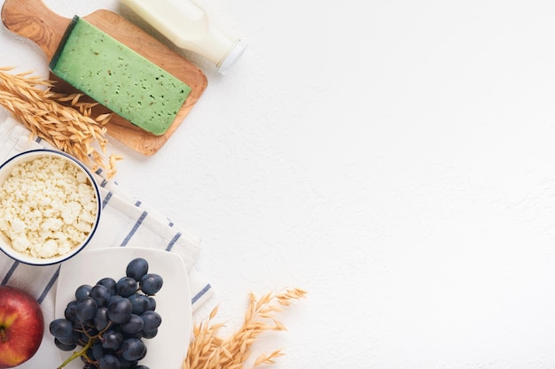 Celebración festiva judía de Shavuot Leche y queso trigo maduro y frutas fondo de madera azul Productos lácteos sobre fondo de hormigón blanco Concepto de Shavuot Vista superior Maqueta