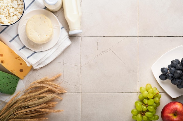 Celebración de la festividad judía de Shavuot Leche y queso trigo maduro y frutas crema viejo fondo de pared de azulejos agrietados Productos lácteos sobre fondo gris Concepto de Shavuot Vista superior Maqueta