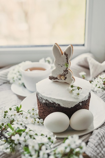 Celebración y fiesta Pastel de Pascua con pan de jengibre huevos de torta casera Conejito de Pascua y postal de ramas floridas