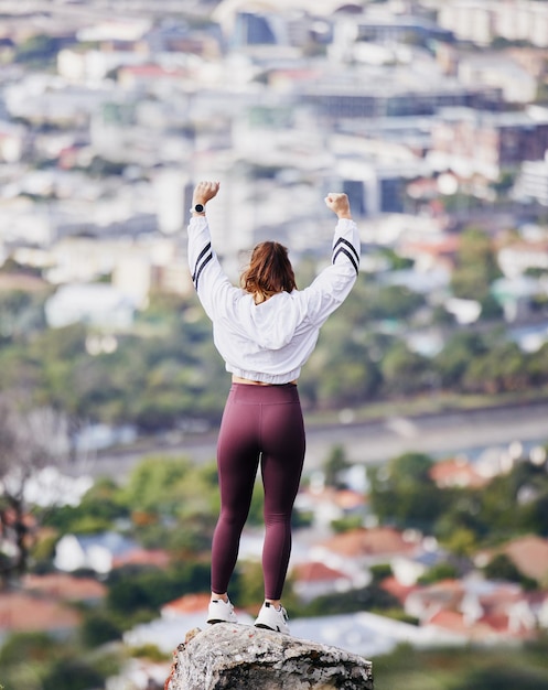 Celebración de fitness y mujer en la montaña con los brazos levantados para el logro de la victoria y los objetivos de ejercicio Bienestar de la ciudad y espalda de niña feliz emocionada después de correr entrenamiento y entrenamiento de maratón