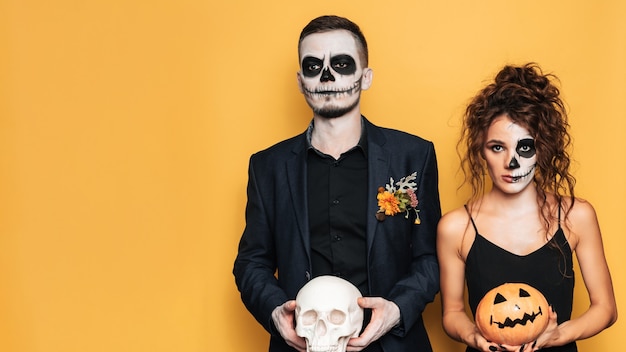 Celebración de Halloween. Una foto de estudio de una joven pareja en disfraces de Halloween festivos y con maquillaje en la cara. Un lugar para su texto, publicidad.