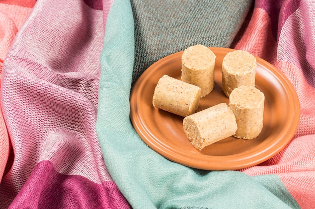 Celebración de junio. Cacahuete brasileño dulce llamado PaÃ§oca en un plato sobre una tela de color.