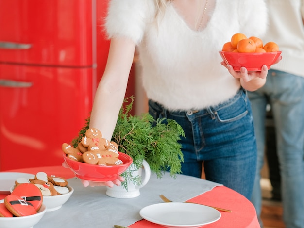 Celebración de Navidad. Señora poniendo mesa festiva con mandarinas y galletas de jengibre