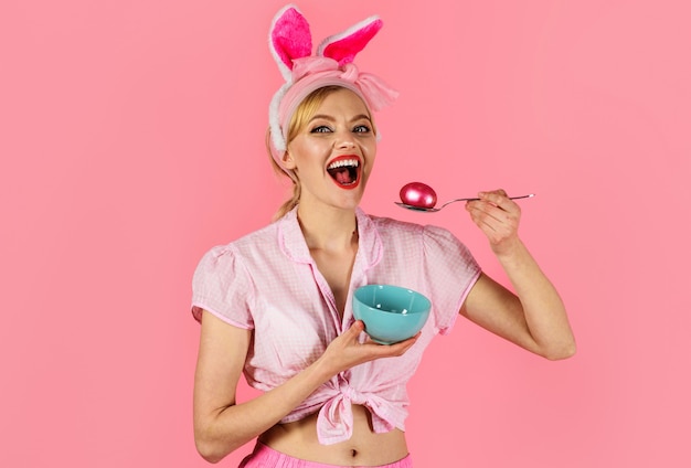 Celebración de Pascua. Mujer con huevo de color. Niña sonriente en orejas de conejo. Huevos de caza.