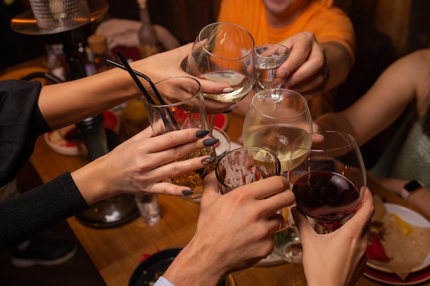 Celebración de personas sosteniendo copas de vino blanco haciendo un brindis