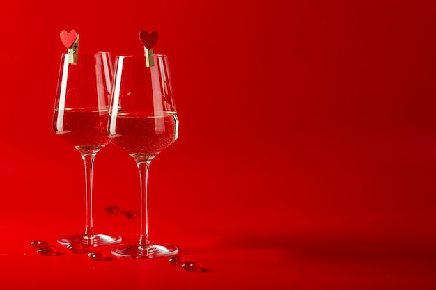 Celebración romántica del día de San Valentín. Dos copas llenas de vino y corazones de cristal decorativo
