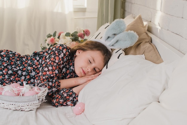 Celebrando a menina da páscoa com orelhas de coelho na cama