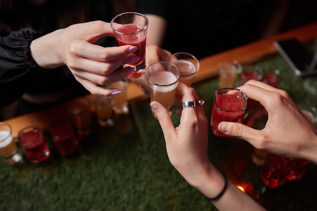 Celebrando com copos de álcool nas mãos amigas felizes se divertindo