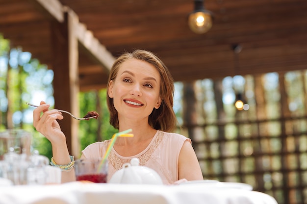 Celebrando cumpleaños. Sonriente mujer de pelo rubio que se siente extremadamente feliz mientras celebraba su cumpleaños