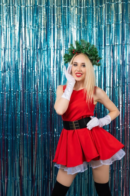 Celebrando la noche de la víspera de la temporada de invierno. Chica rubia vestida como Santa Claus sobre un fondo de oropel