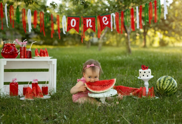 Celebrando el primer cumpleaños de un niño en la naturaleza con un pastel y sandías