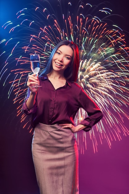 Celebrando la víspera de año nuevo tiro vertical de una joven mujer asiática feliz con vaso de