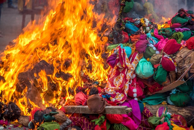 Celebrar Holika Dahan adorando y prendiendo fuego a troncos de madera o coco, también conocido como el festival de colores Holi o el festival de compartir