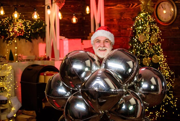 Celebremos. decoración de fiesta. hombre barbudo sombrero de santa claus. celebración de vacaciones de invierno. Feliz Navidad. feliz año nuevo 2020. regalos y regalos de navidad. globos de fiesta de hombre de santa alegre.