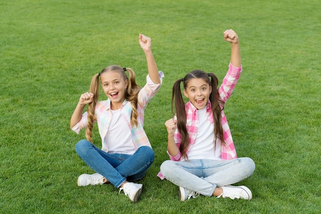 Celebremos. Los niños felices hacen gestos de ganador. Los niños pequeños celebran en la hierba verde. Celebrando la victoria. Celebración de fiestas. Diversión y alegría. Sal y festeja. Celebra el verano conmigo.