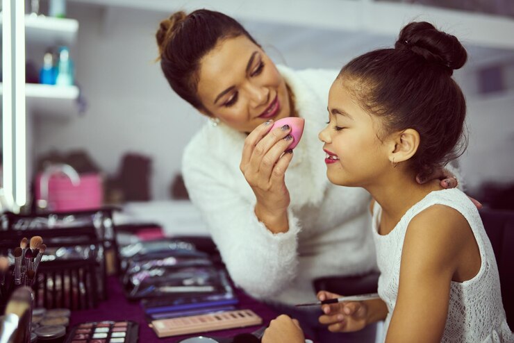Foto celebridade nos bastidores ou maquiagem com menina feliz e estilista no estúdio se preparando nos bastidoras cosméticos e fundação de modelo infantil com mulher no set para preparação criativa de talento