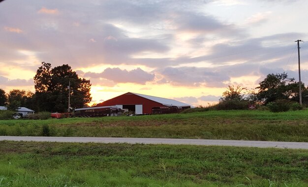 Foto celeiro no campo contra o céu durante o pôr-do-sol
