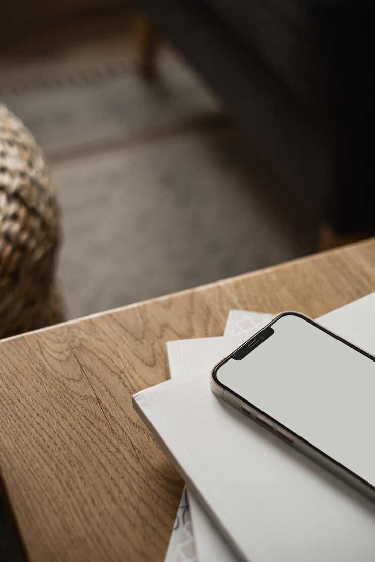 Foto celular com tela em branco, folhas de papel na mesa de madeira e carpete