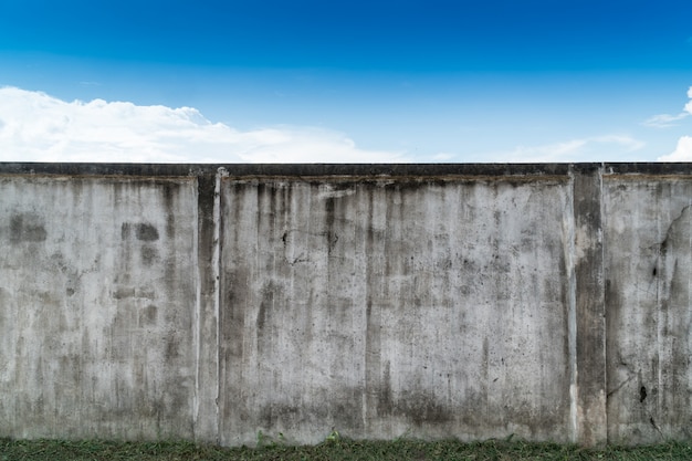 Cemento gris agrietado viejo o muro de cemento con el cielo azul como fondo. Grunge enyesado de fondo con textura de estuco.