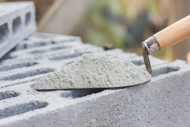 Foto cemento en polvo con una paleta puesta en el ladrillo para la construcción