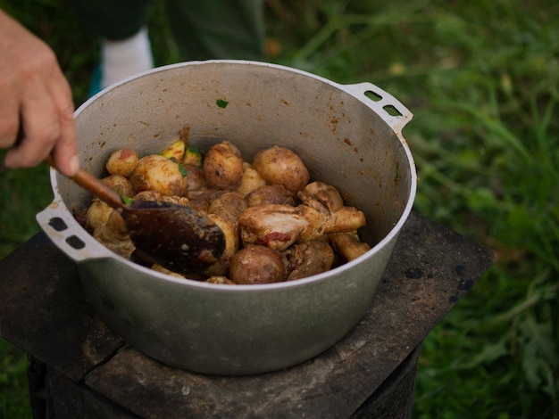 Cena al fuego patatas con calabacín y pollo se cocinan en un caldero en la calle