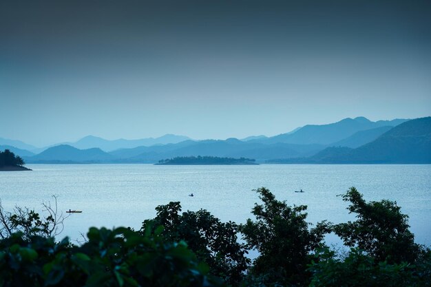 Foto cena azul do reservatório de kaeng krachan com um barco de pesca e uma canoa de remo turística