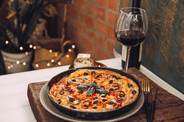 Cena en el balcón con una copa de vino tinto y pizza italiana casera