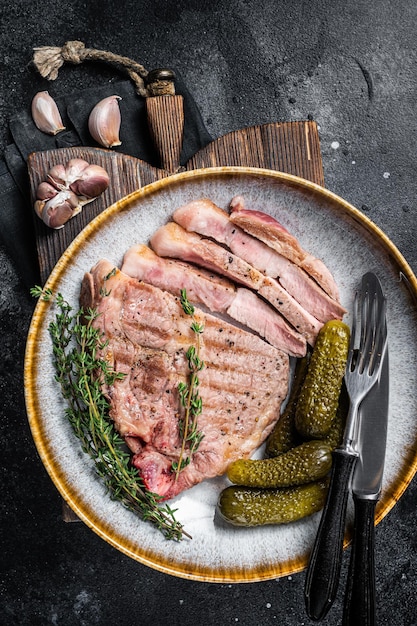 Cena de barbacoa Filetes de cerdo de carne de cuello en plato con hebs Fondo negro Vista superior