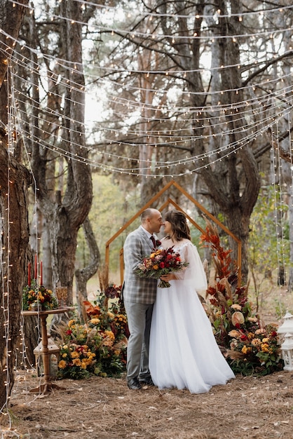 Cena de boda de una pareja de recién casados en el bosque de otoño en el fondo de la ceremonia de la boda