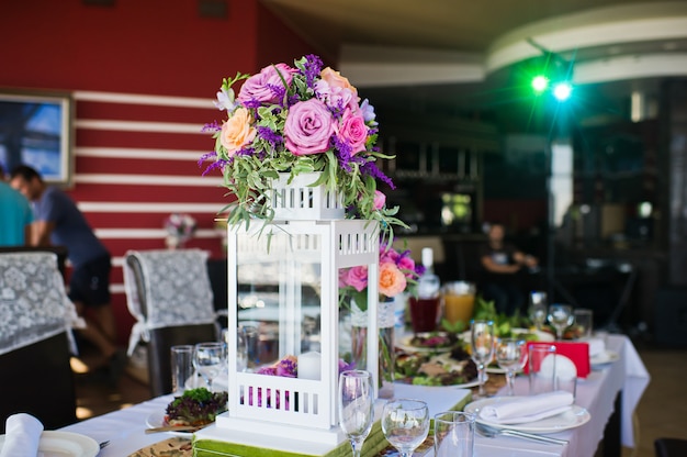 Foto cena de boda en el restaurante, mesas decoradas con jarrones de rosas.