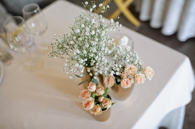 Cena de boda en el restaurante, mesas decoradas con jarrones de rosas.