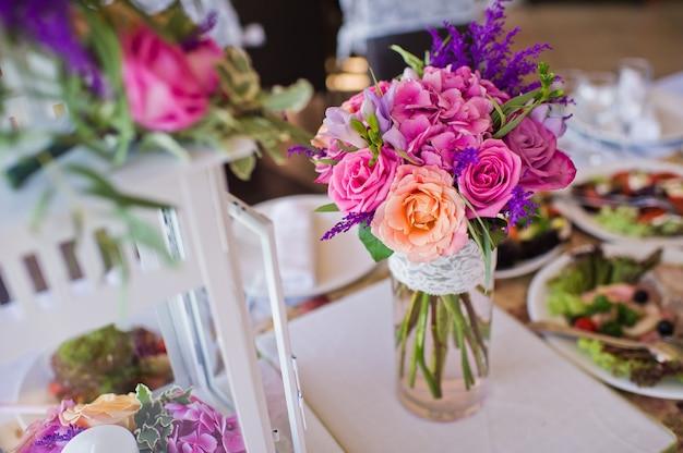 Foto cena de boda en el restaurante, mesas decoradas con jarrones de rosas.