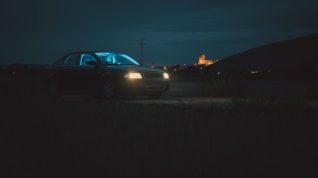 Foto cena cinematográfica de um homem dirigindo um carro com um castelo atrás ao entardecer interior iluminado com luz azul