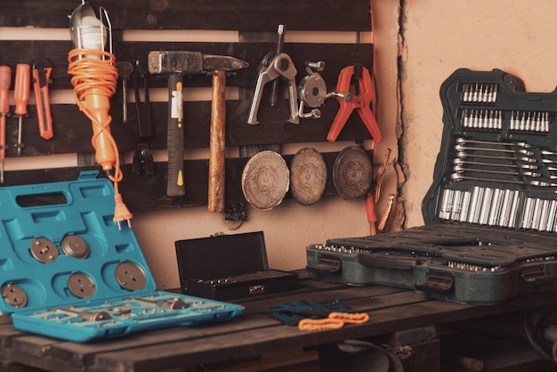 Cena da oficina. Ferramentas na mesa e no tabuleiro. Garagem, loja de automóveis. Ferramenta especial de reparo de veículos. Caixas da caixa de ferramentas. Bicos, chaves de fenda e interruptores automáticos