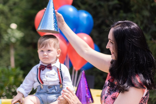 Cena de aniversário de primeiro ano de mãe e filho cheia de balões, chapéus de festa, decorações de aniversário