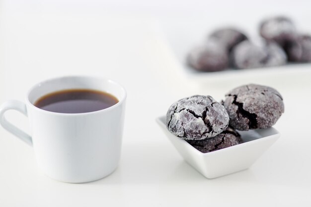 Cena de design mínimo uma xícara de café e biscoito de chocolate escuro sobre fundo branco liso inclui espaço de cópia