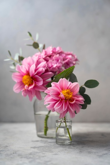 Cena de flores rosa de vida morta Flores de hortênsia rosa e dálias em vaso de vidro em fundo neutro foco seletivo suave