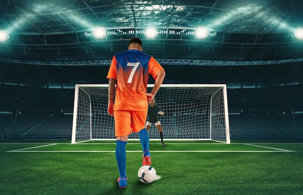 Cena de futebol no jogo noturno com jogador de uniforme laranja chutando o pênalti