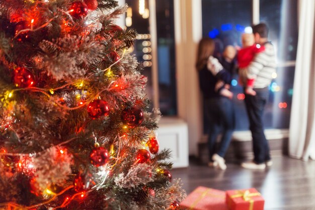 Cena de Natal com família feliz de quatro árvores presentes e janela